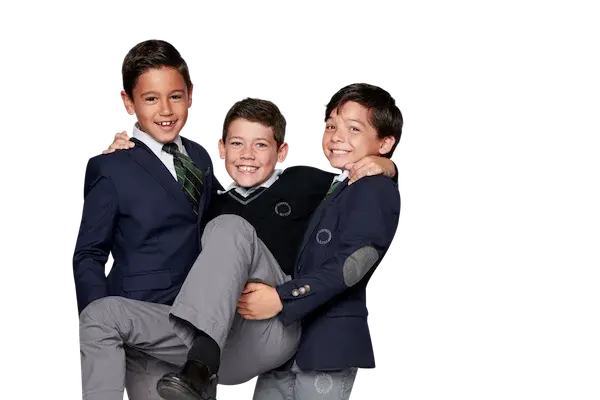 Tres estudiantes del colegio vistiendo uniforme escolar azul marino se abrazan sonriendo en actitud de compañerismo y amistad.